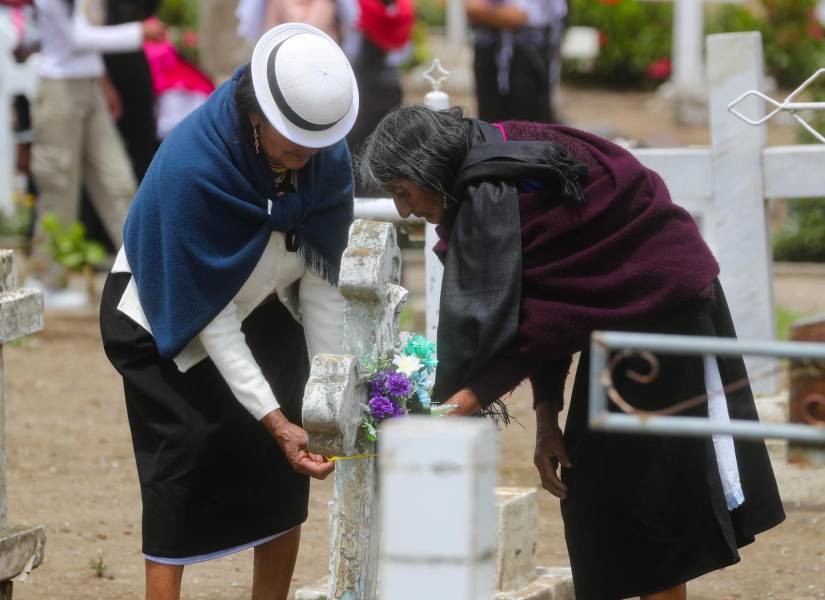 Dos mujeres decoran una tumba durante la conmemoración del Día de los Difuntos este sábado, en Punín, parroquia de Riobamba.